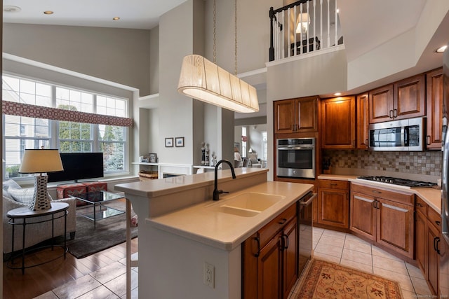 kitchen with appliances with stainless steel finishes, open floor plan, a sink, and light countertops