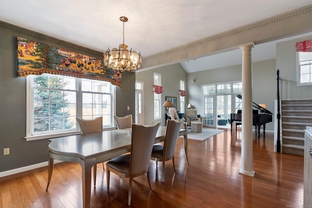 dining area featuring decorative columns, baseboards, hardwood / wood-style floors, stairs, and vaulted ceiling