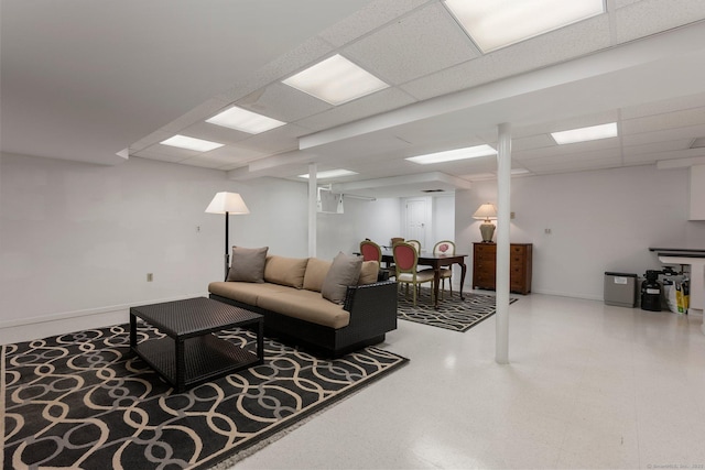 living area featuring a drop ceiling and baseboards