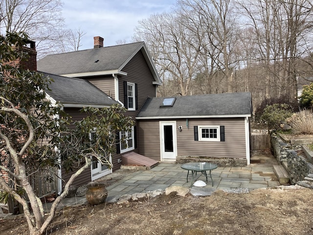 rear view of house with fence, a shingled roof, and a patio area