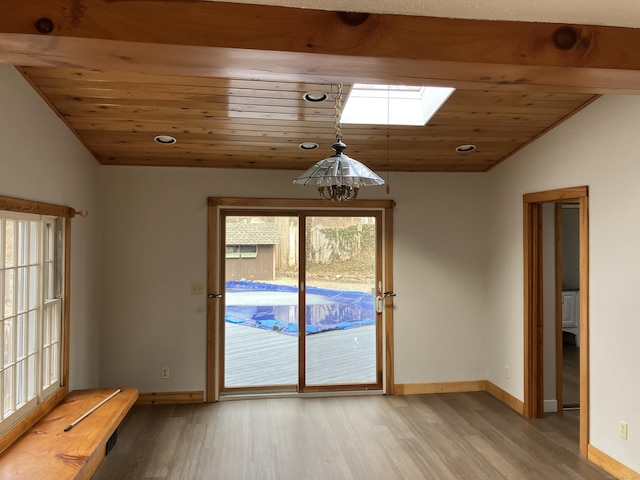 entryway featuring light wood finished floors, vaulted ceiling with skylight, wood ceiling, and baseboards