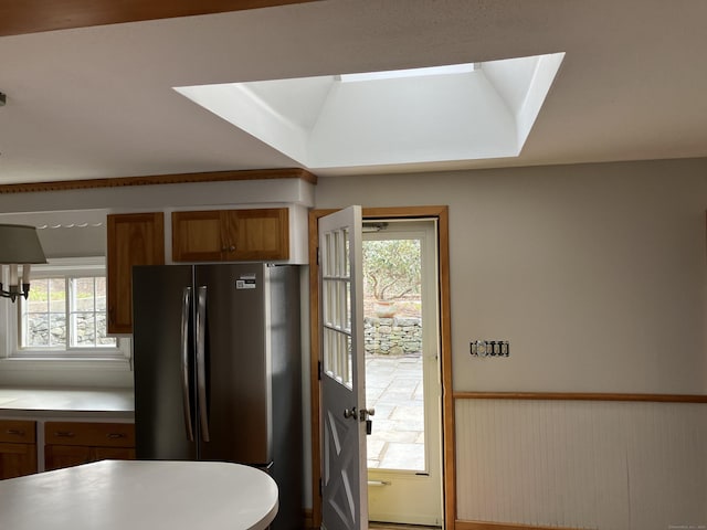 kitchen featuring light countertops, a healthy amount of sunlight, freestanding refrigerator, and wainscoting