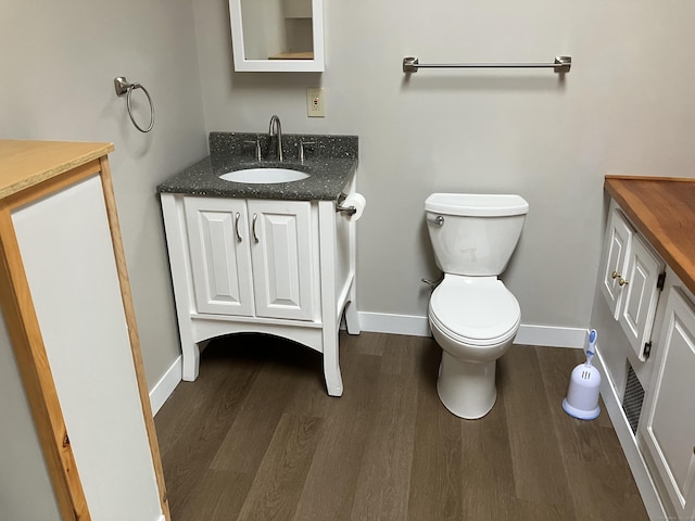 bathroom with toilet, vanity, baseboards, and wood finished floors