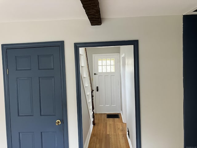 entryway featuring beamed ceiling, light wood-style flooring, visible vents, and baseboards