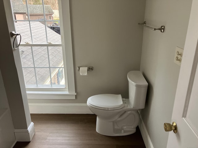 bathroom with plenty of natural light, toilet, baseboards, and wood finished floors