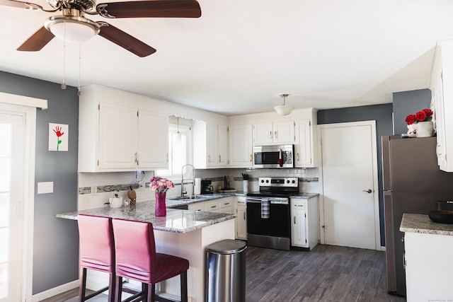 kitchen featuring a peninsula, a sink, white cabinetry, appliances with stainless steel finishes, and decorative backsplash