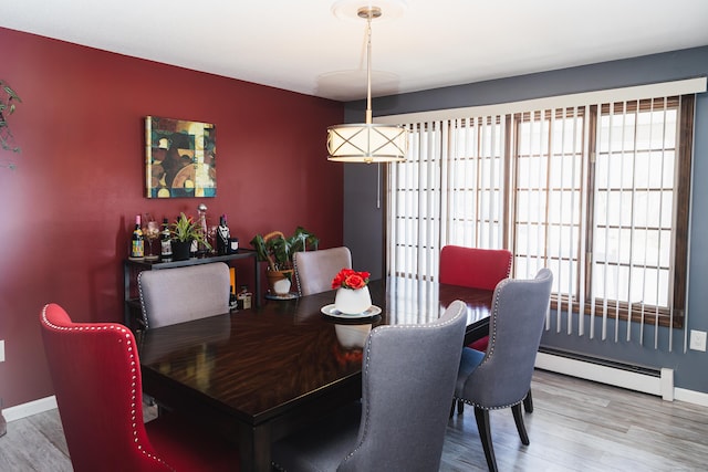 dining room with a baseboard heating unit, plenty of natural light, and wood finished floors