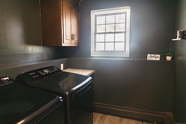 laundry room featuring wood finished floors, washing machine and dryer, and cabinet space