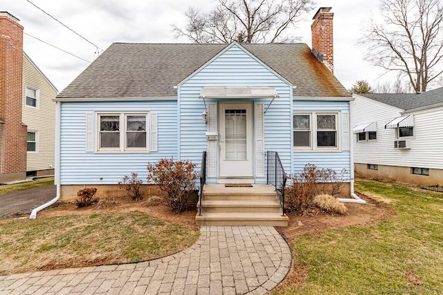 bungalow with cooling unit, a chimney, a front yard, and a shingled roof