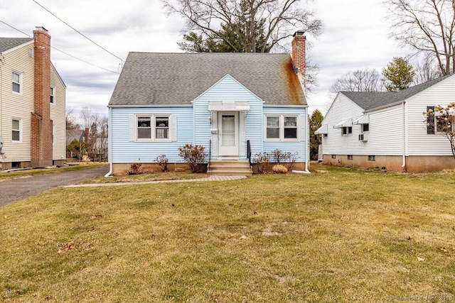 view of front of home with driveway, a chimney, a front yard, and roof with shingles