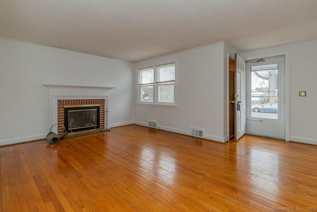 unfurnished living room with visible vents, baseboards, light wood-style floors, and a fireplace