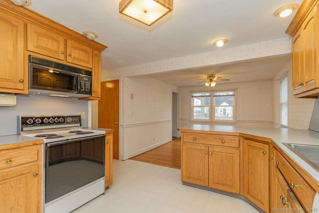 kitchen featuring wallpapered walls, a peninsula, black microwave, and white electric stove