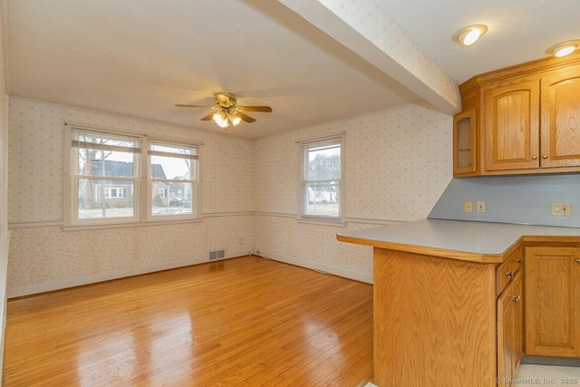 kitchen featuring light wood finished floors, wallpapered walls, and a wealth of natural light