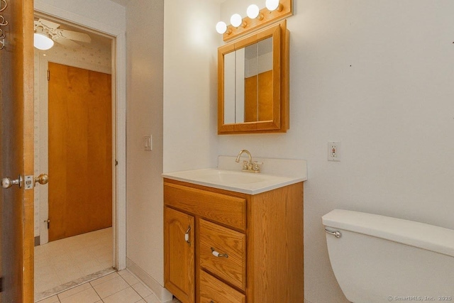 half bath with toilet, vanity, and a ceiling fan