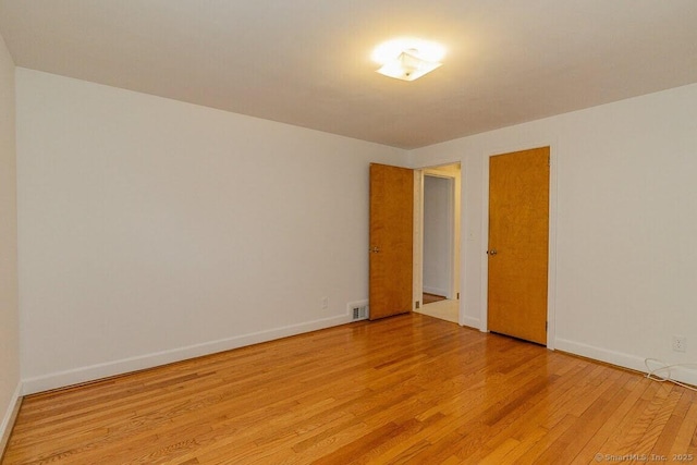 unfurnished room featuring light wood-style flooring, baseboards, and visible vents