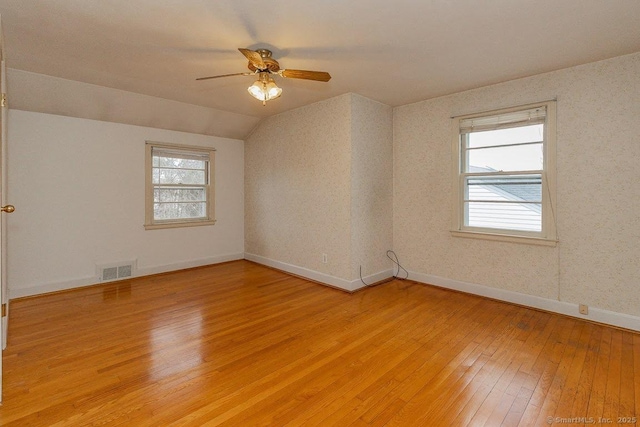 spare room featuring wallpapered walls, light wood-style flooring, a healthy amount of sunlight, and ceiling fan