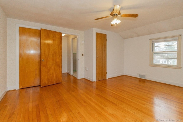 unfurnished bedroom featuring light wood finished floors, visible vents, baseboards, and vaulted ceiling