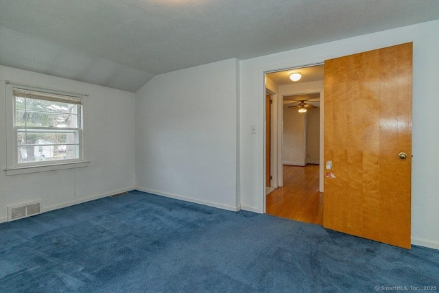 carpeted empty room featuring visible vents, ceiling fan, baseboards, and lofted ceiling