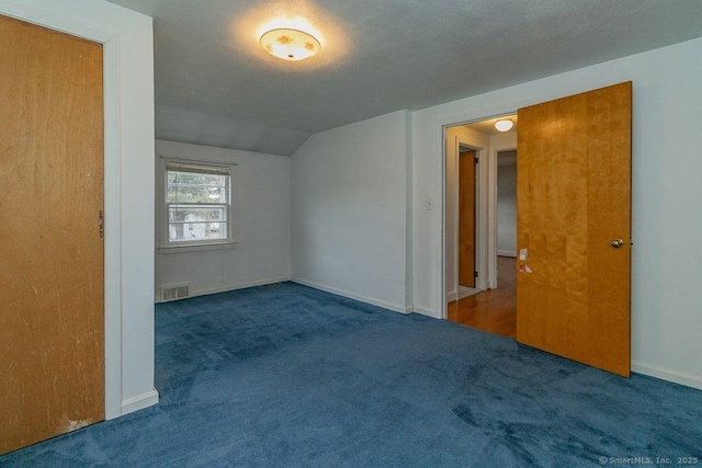 unfurnished room featuring visible vents, a textured ceiling, carpet, baseboards, and vaulted ceiling