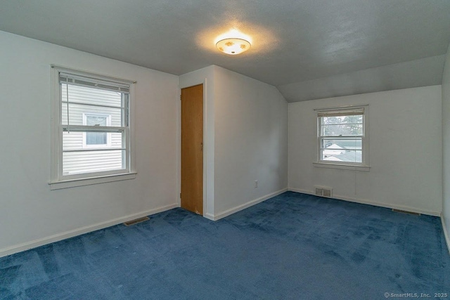 interior space featuring visible vents, baseboards, carpet, and vaulted ceiling