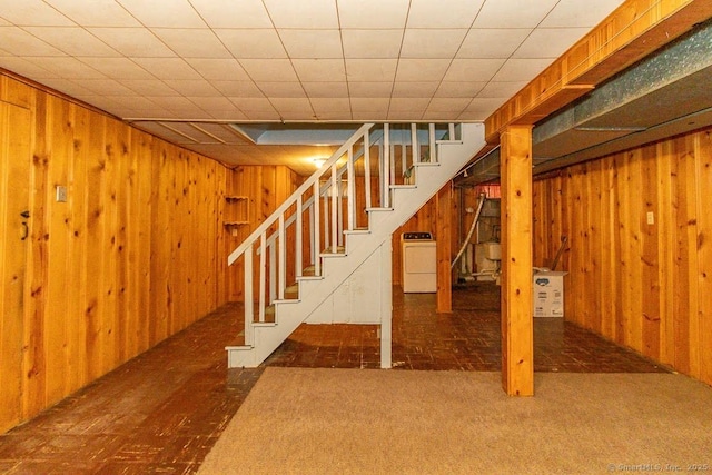 finished below grade area featuring washer / clothes dryer, carpet, wood walls, and stairs