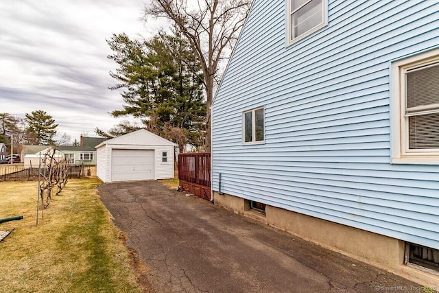 view of home's exterior featuring a lawn, driveway, fence, an outdoor structure, and a garage