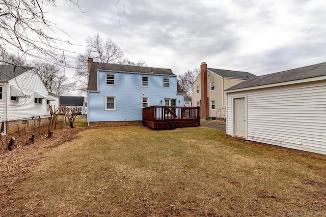 back of property with a deck, a chimney, and a yard