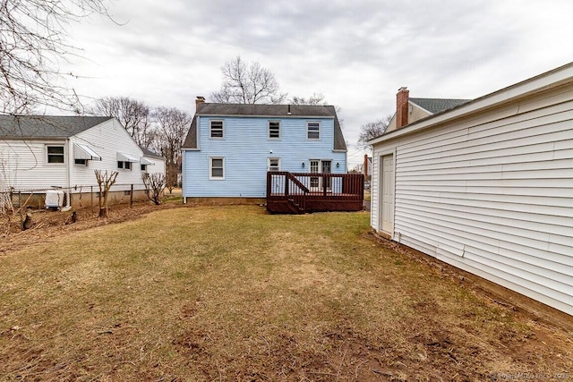 rear view of property featuring a wooden deck, a lawn, a chimney, and fence