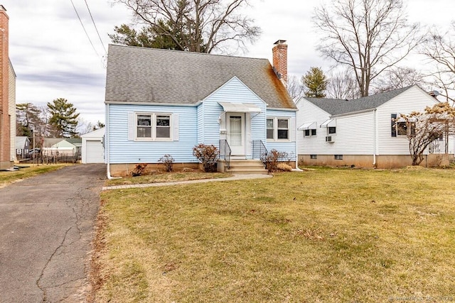 cape cod home featuring aphalt driveway, a chimney, a front yard, and a shingled roof