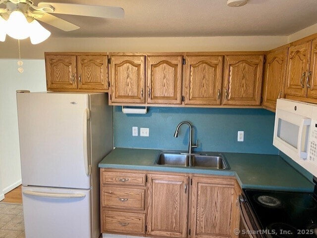 kitchen with brown cabinets, white appliances, ceiling fan, and a sink