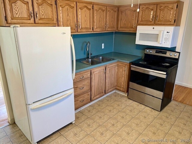 kitchen with white appliances, brown cabinetry, and a sink