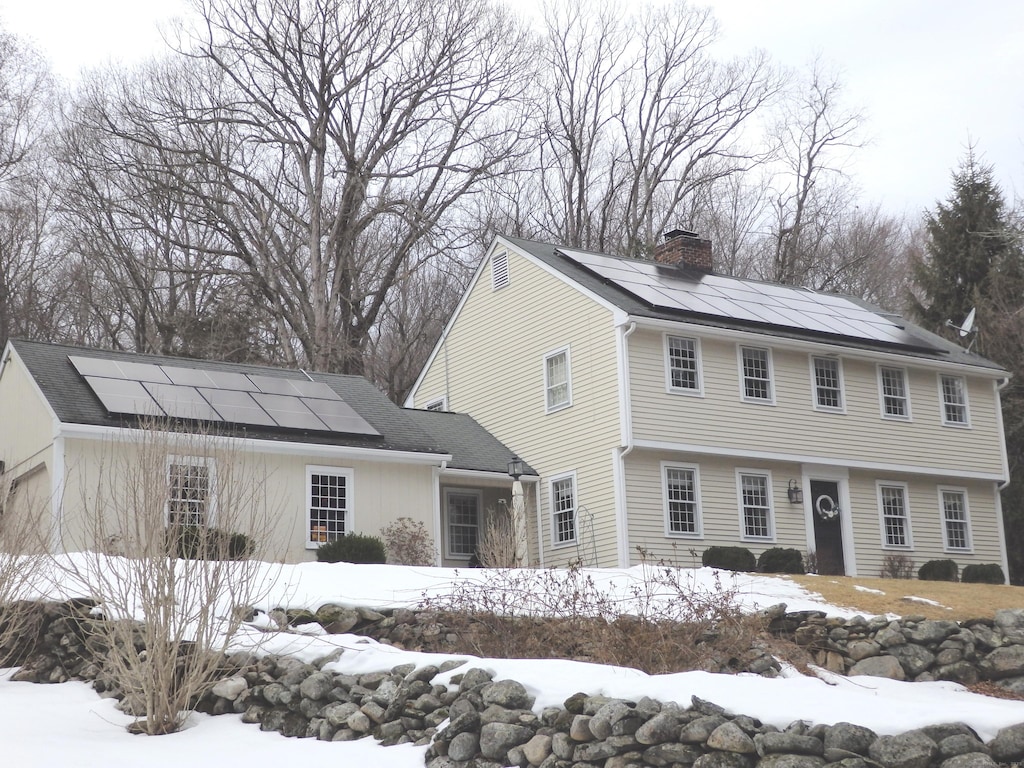 colonial house with solar panels and a chimney