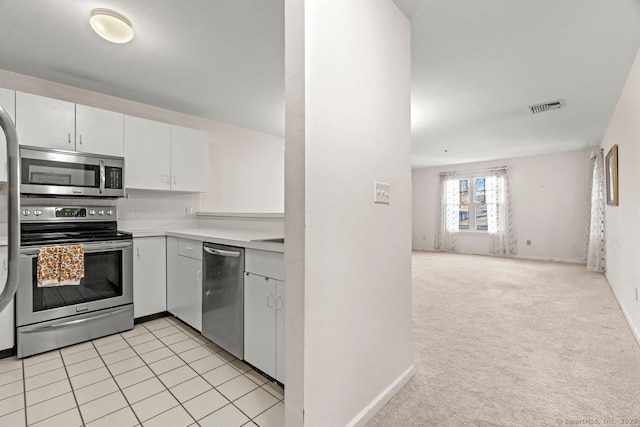 kitchen with visible vents, light countertops, light carpet, stainless steel appliances, and white cabinetry