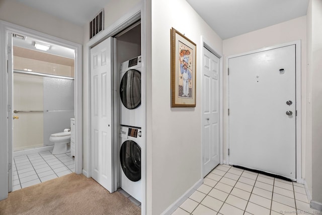 clothes washing area with visible vents, light colored carpet, laundry area, light tile patterned flooring, and stacked washer / drying machine