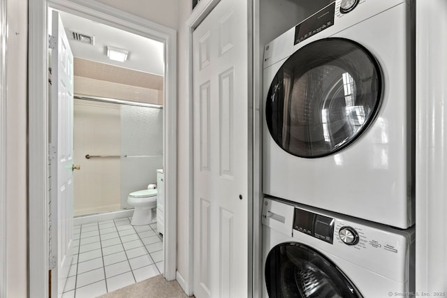 clothes washing area with light tile patterned floors, visible vents, laundry area, and stacked washer and dryer