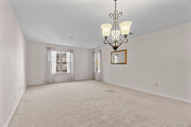 spare room featuring light carpet, baseboards, and an inviting chandelier