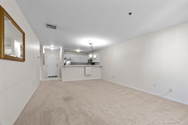 unfurnished living room with visible vents, baseboards, light colored carpet, and a notable chandelier