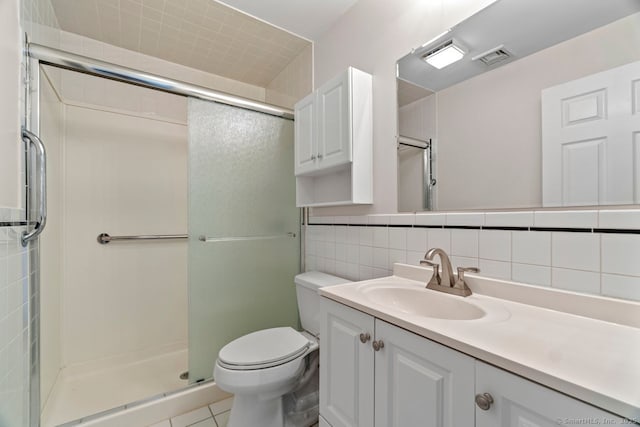 bathroom featuring visible vents, a shower stall, toilet, vanity, and tile walls