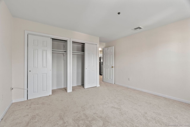 unfurnished bedroom featuring visible vents, light colored carpet, and baseboards