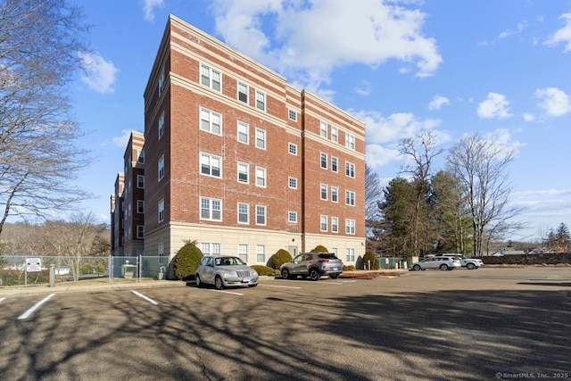 view of building exterior with fence and uncovered parking