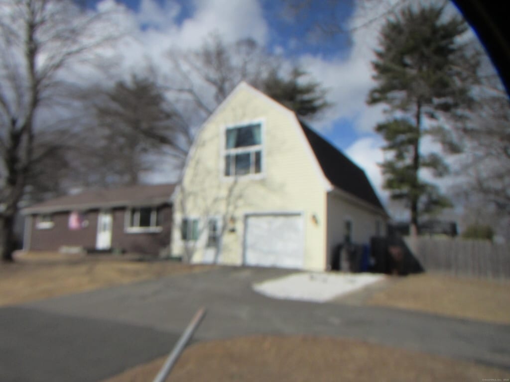 view of side of home with a garage, driveway, and a gambrel roof