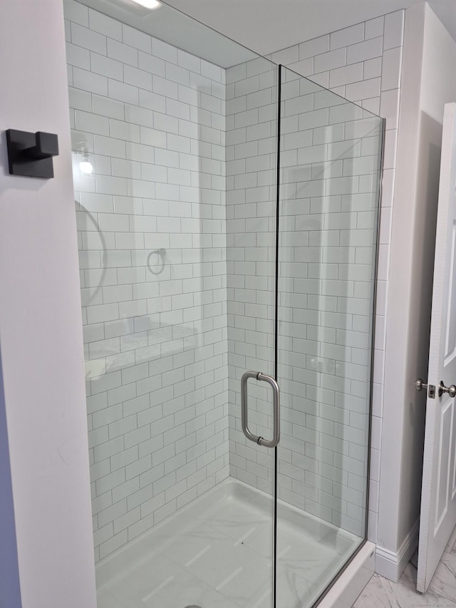 bathroom featuring marble finish floor and a shower stall