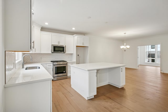 kitchen featuring decorative backsplash, a kitchen island, stainless steel appliances, light wood-style floors, and a sink