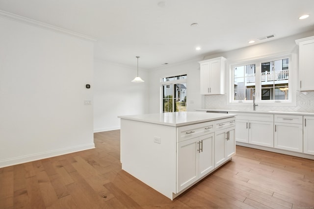 kitchen featuring decorative backsplash, visible vents, a sink, and light wood finished floors