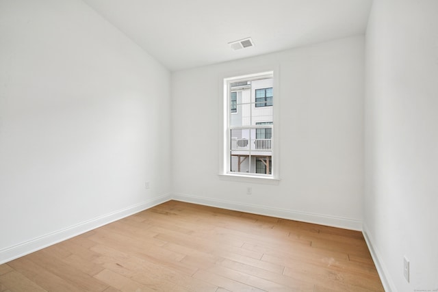 unfurnished room featuring visible vents, light wood-style flooring, and baseboards