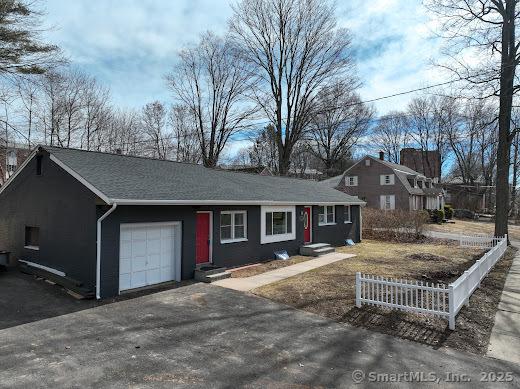 ranch-style house featuring an attached garage, driveway, entry steps, and fence