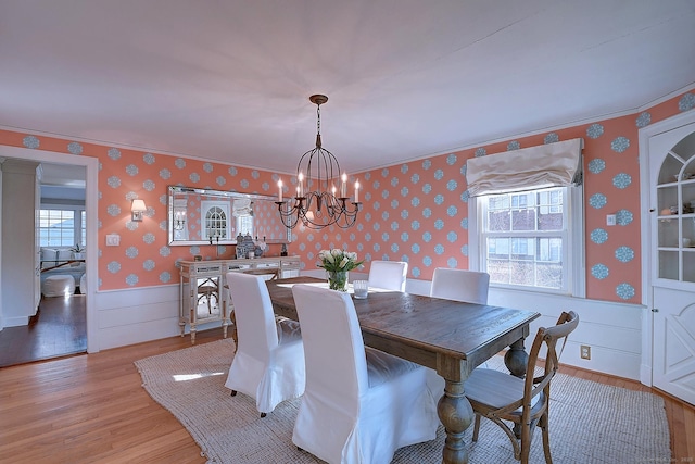 dining area featuring a notable chandelier, a wainscoted wall, wallpapered walls, and light wood-style floors