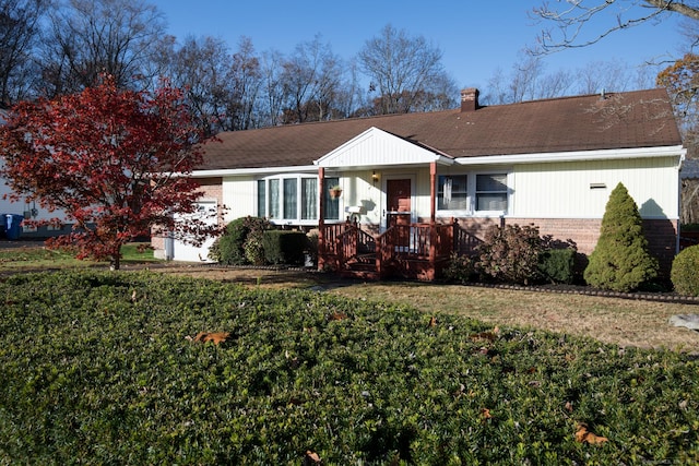 ranch-style home featuring brick siding, a chimney, covered porch, and a front lawn