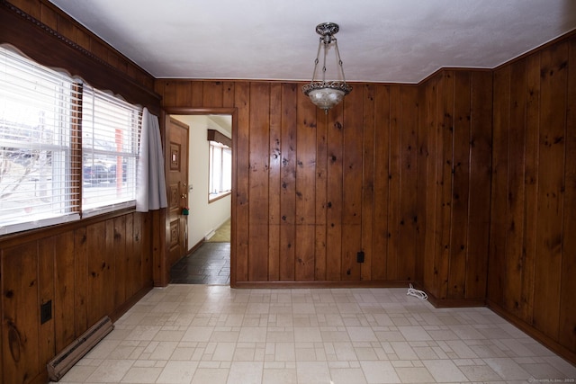 unfurnished room featuring a baseboard radiator, baseboards, and wooden walls