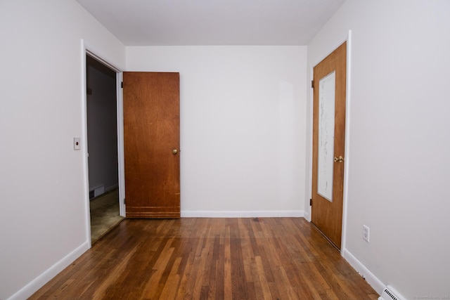 spare room with visible vents, a baseboard radiator, baseboards, and wood finished floors